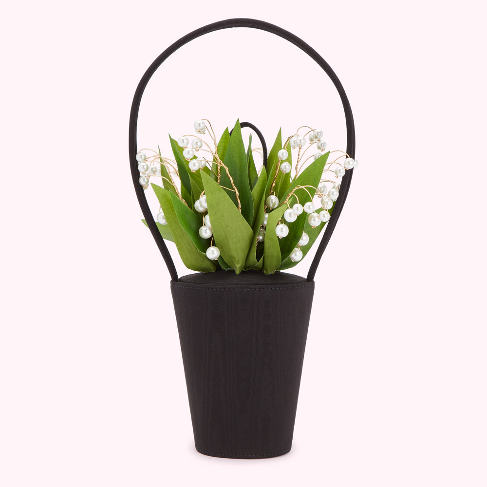 Black handbag shaped like a vase with a bouquet of lilies of the valley and pearls.