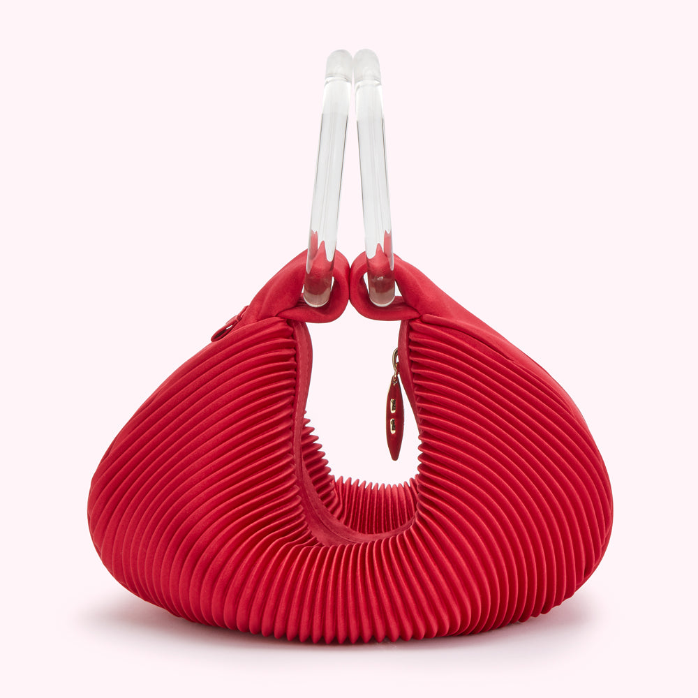 Red pleated handbag with clear acrylic handles.