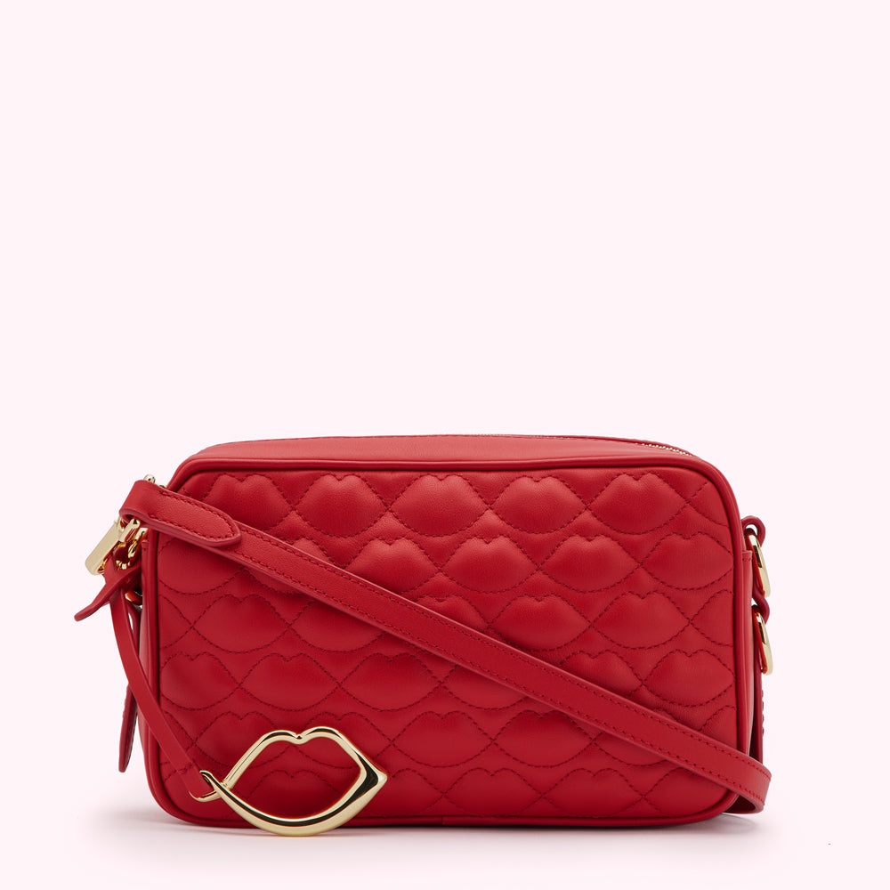Red quilted crossbody bag with gold lip charm.