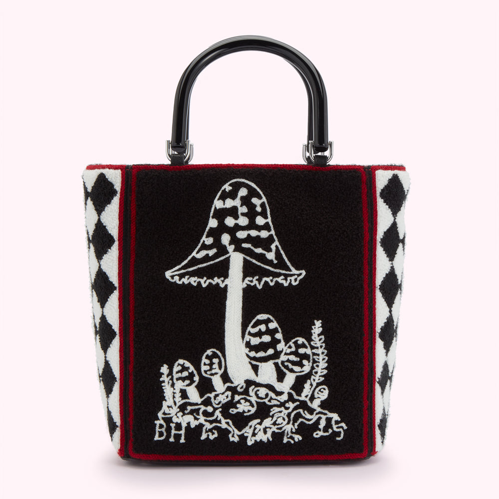 Black and white embroidered mushroom tote bag with black and white harlequin trim and a black handle.