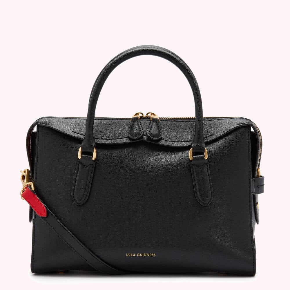 Black Lulu Guinness leather satchel bag with gold hardware and a red and black detachable strap.
