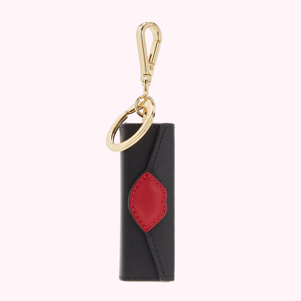 Black leather key fob with red lip detail and gold clasp.
