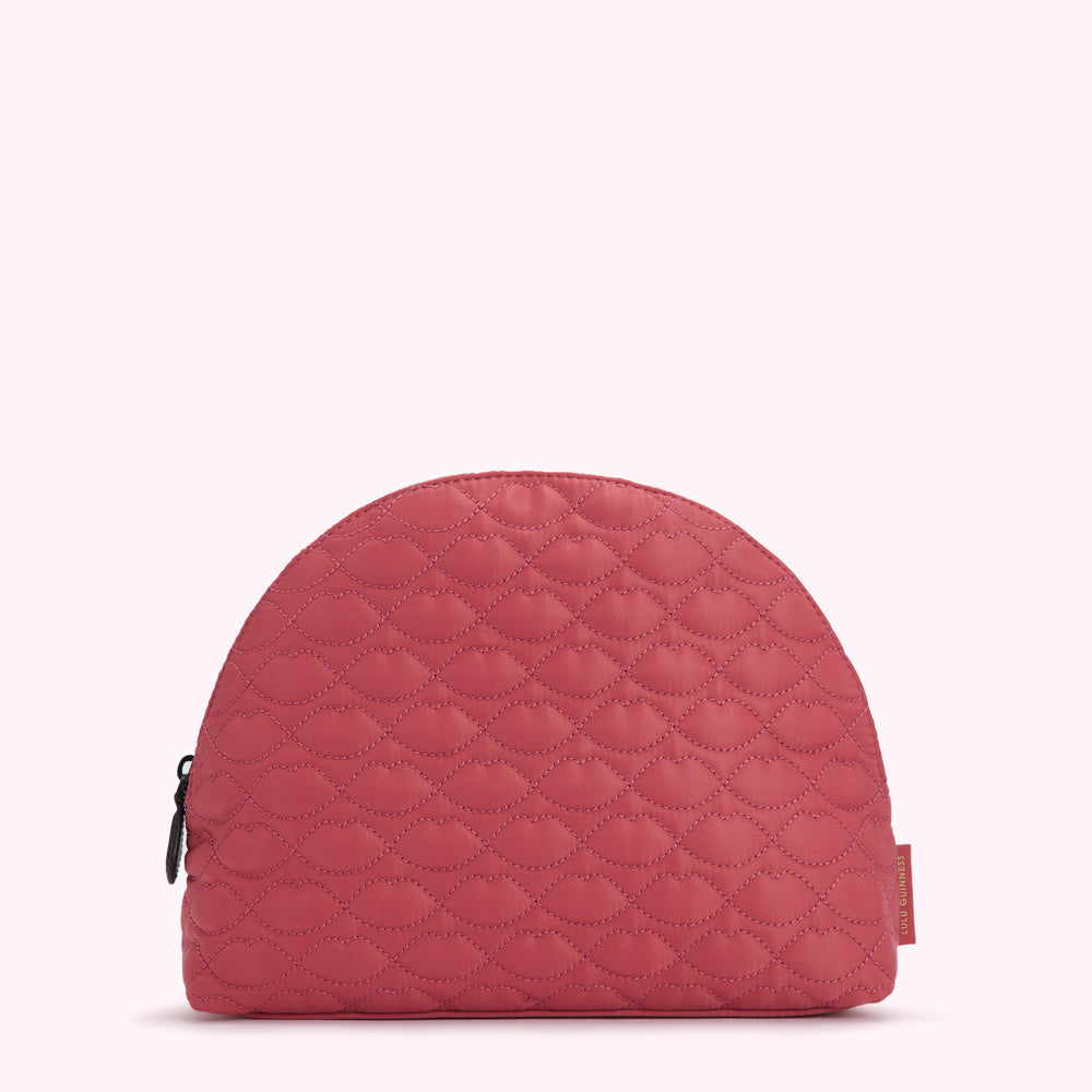Half-moon shaped quilted cosmetic bag in dusty rose with a lip print.