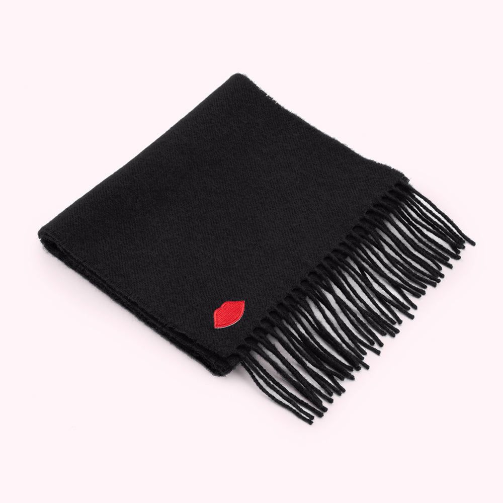 Black fringed scarf with a small red lip design.