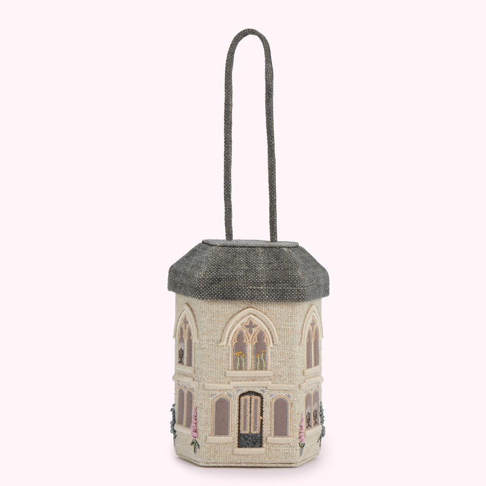 A beige house-shaped handbag with a gray roof and handle, embroidered with floral details.