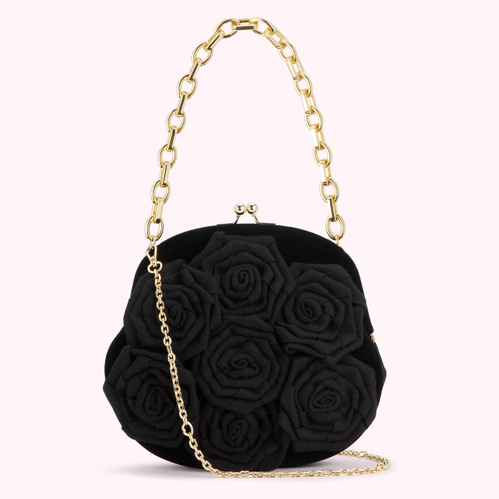 Black velvet clutch purse adorned with black fabric roses and a gold chain strap.