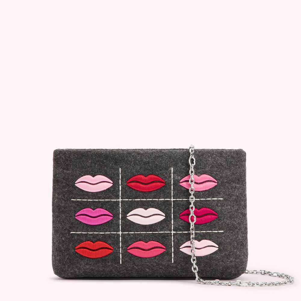 Gray felt clutch with a silver chain strap, featuring a tic-tac-toe grid of embroidered lips in varying shades of pink and red.