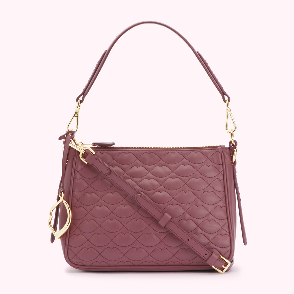 A dusty rose quilted leather shoulder bag with a gold-toned zipper and strap. The quilting is in the shape of lips.