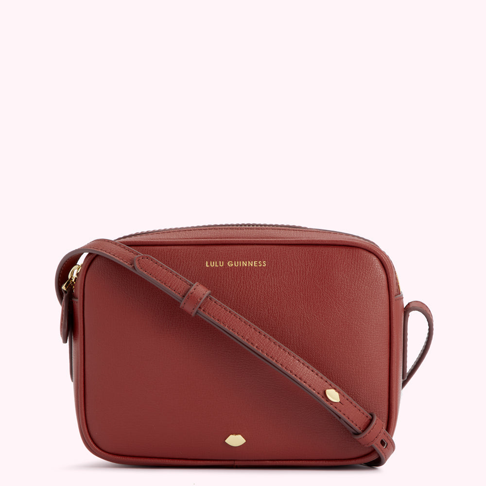 A burnt orange Lulu Guinness crossbody bag.