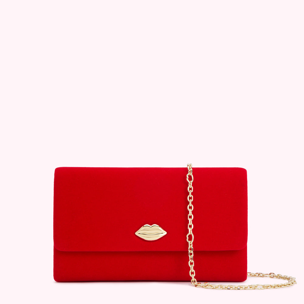 Red velvet clutch with gold lip-shaped clasp and chain strap.