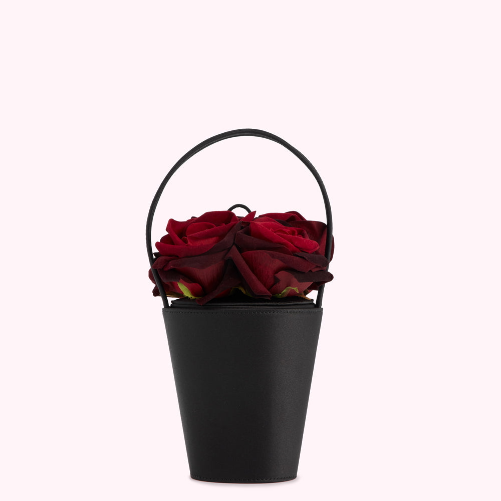 Black bucket bag with a handle, filled with dark red roses.