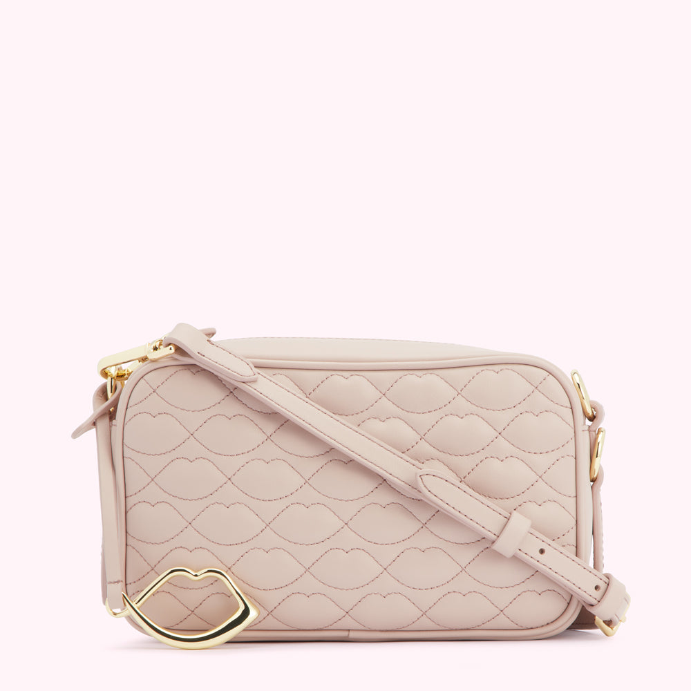 Pale pink quilted crossbody bag with gold lip-shaped detail.