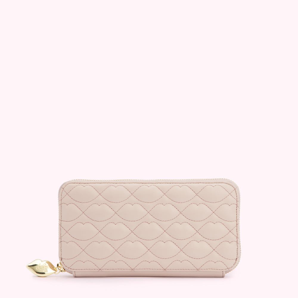 Pale pink quilted zip-around wallet with a lip pattern and gold charm.