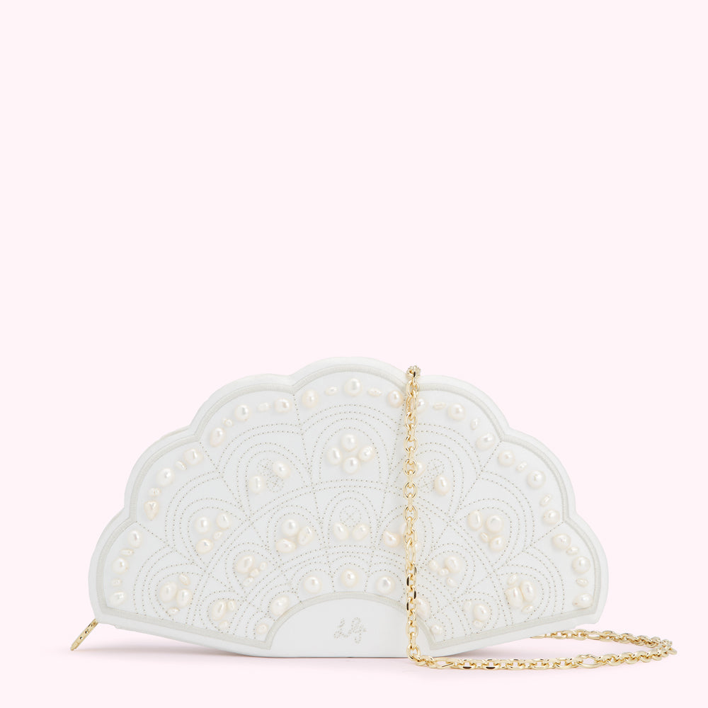 White fan-shaped clutch adorned with pearls and a gold chain strap against a light pink background.