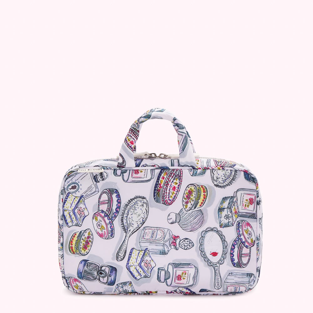 White travel cosmetic bag with a handle and a zipper closure, featuring a colorful illustration of various beauty products.