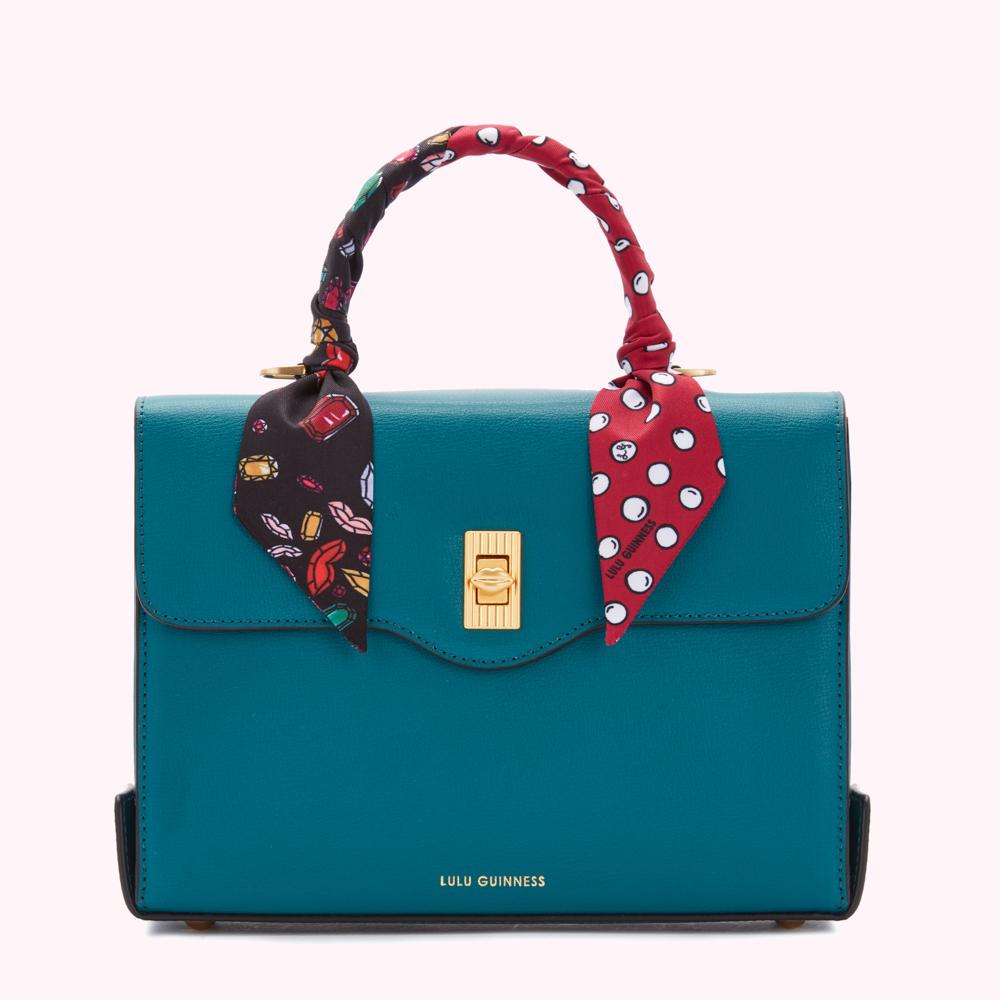 Teal Lulu Guinness satchel with a red and black patterned scarf wrapped around the handle.