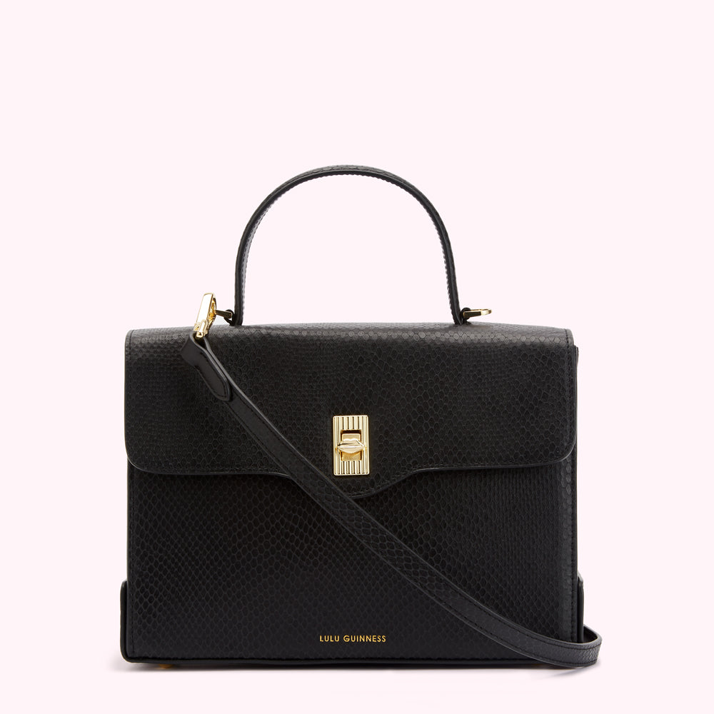 Black Lulu Guinness top-handle satchel bag with gold hardware and crossbody strap against a white background.