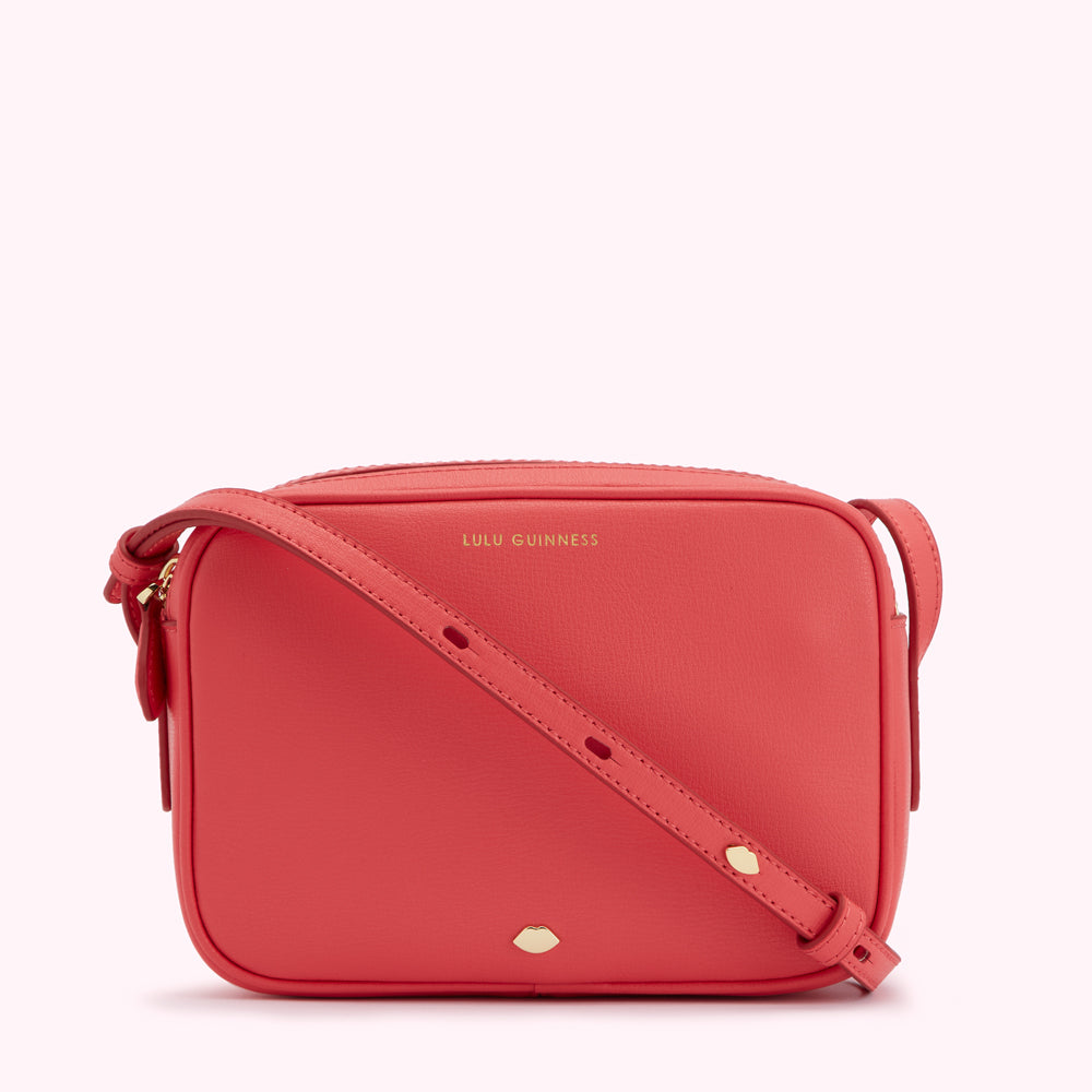 Coral pink Lulu Guinness crossbody bag with gold hardware.