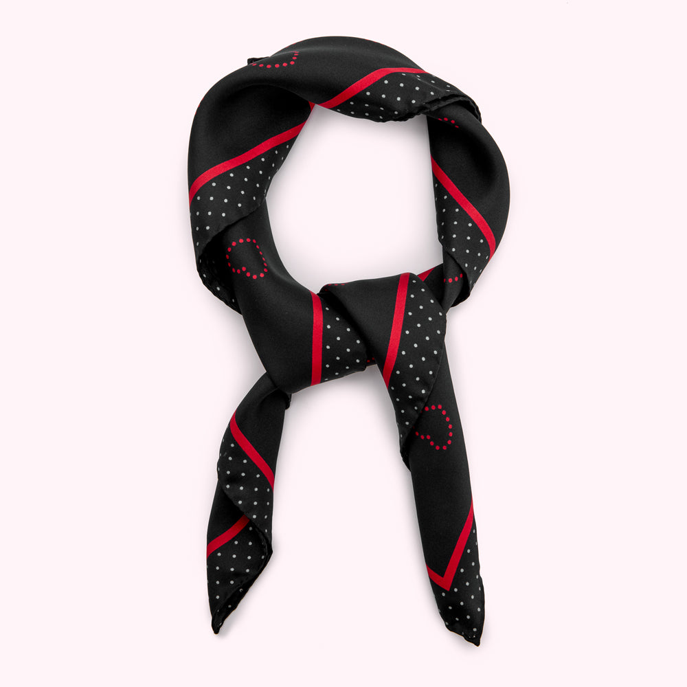 Black silk scarf with red and gray polka dots and stripes, tied in a knot.