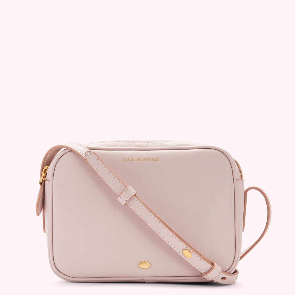 A pale pink Lulu Guinness crossbody bag with gold hardware.