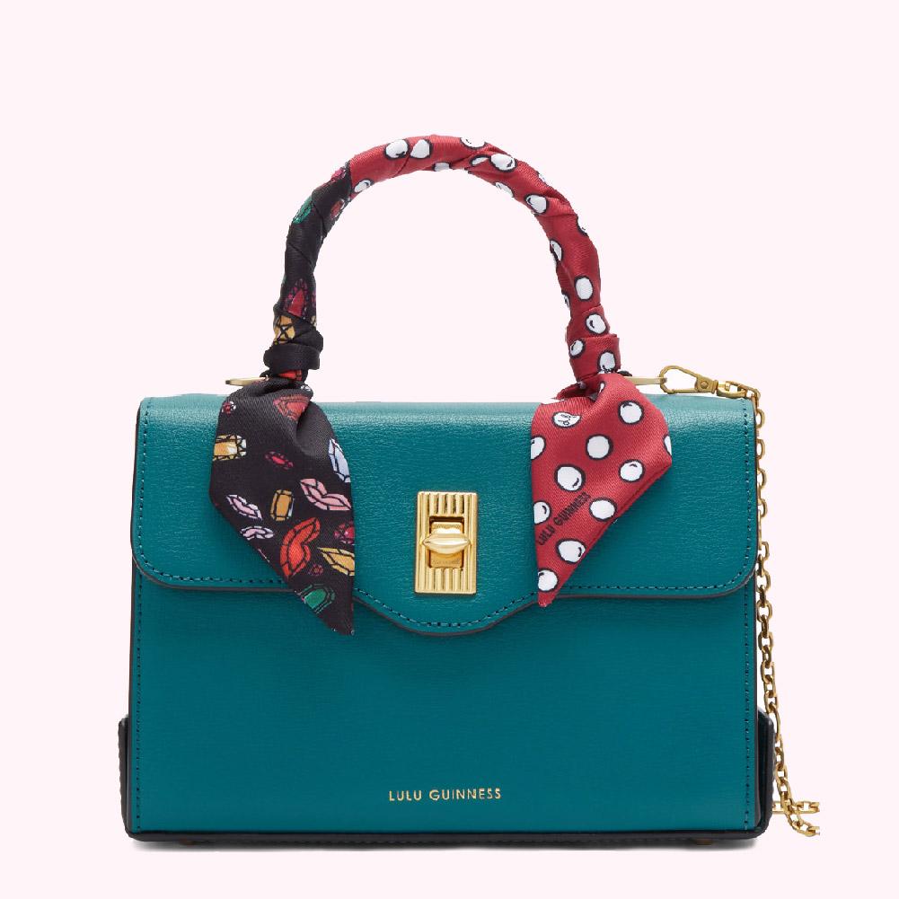 Teal Lulu Guinness handbag with a patterned scarf handle and gold chain.