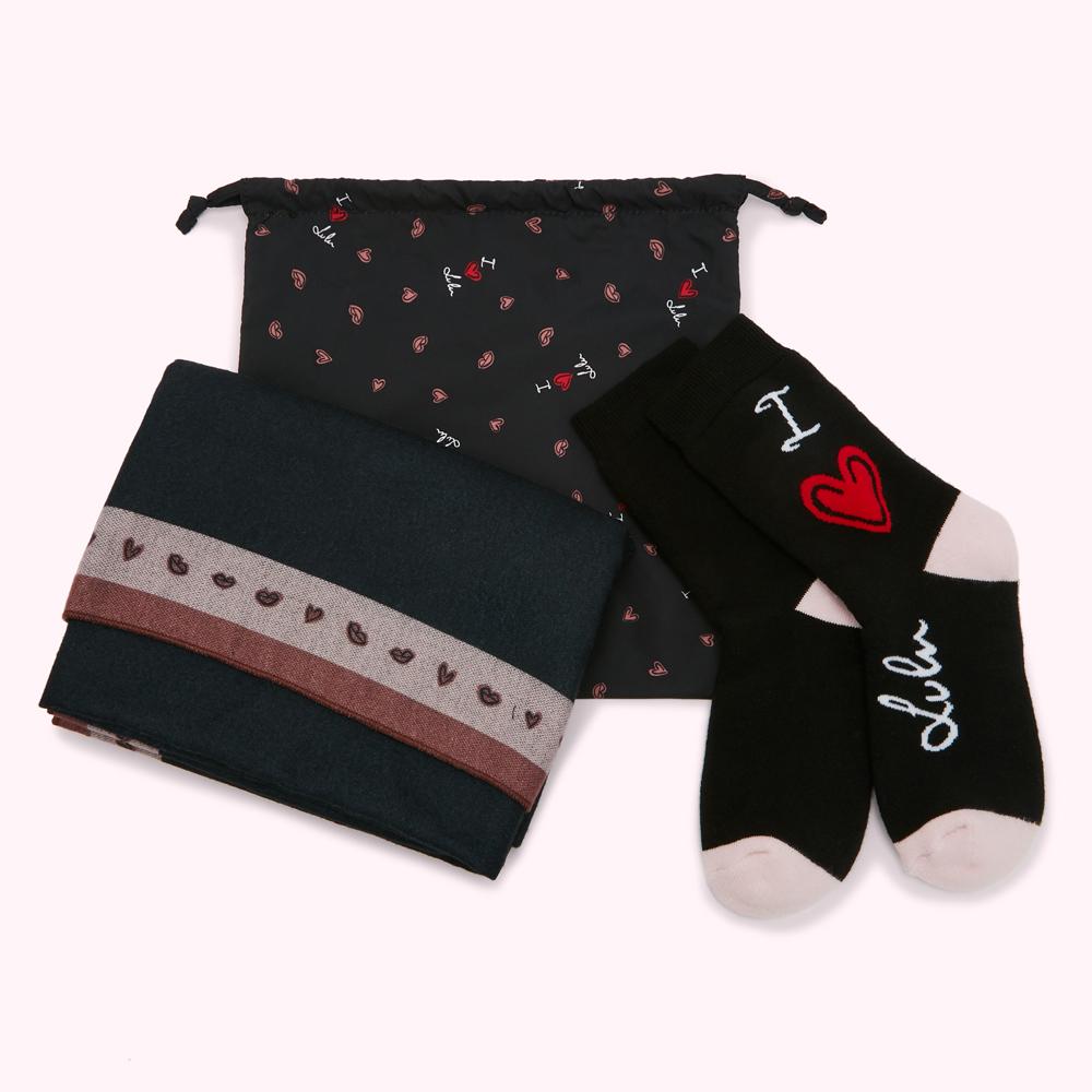 Dark teal scarf with a mauve band of hearts and lips, black socks with "I love Lulu" written on them, and a black gift bag with a repeating pattern of hearts and lips; all on a white background.