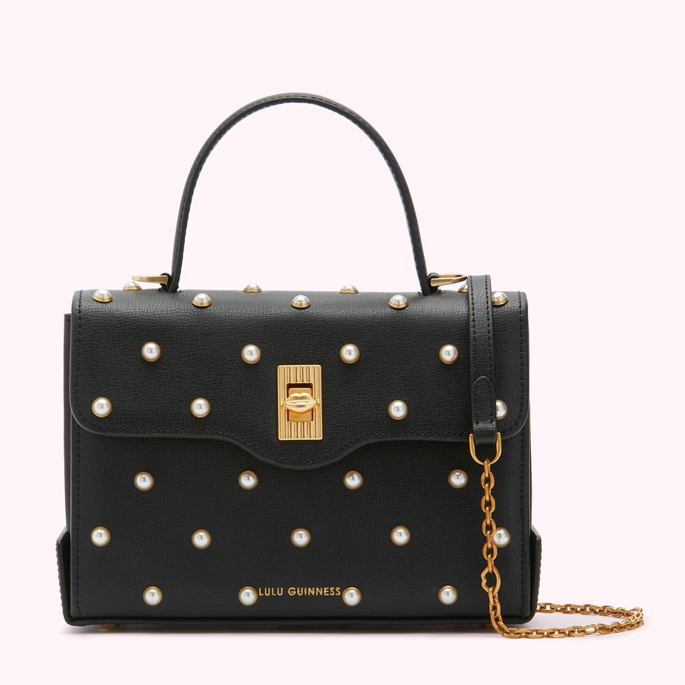Black Lulu Guinness satchel bag adorned with pearls and gold hardware.
