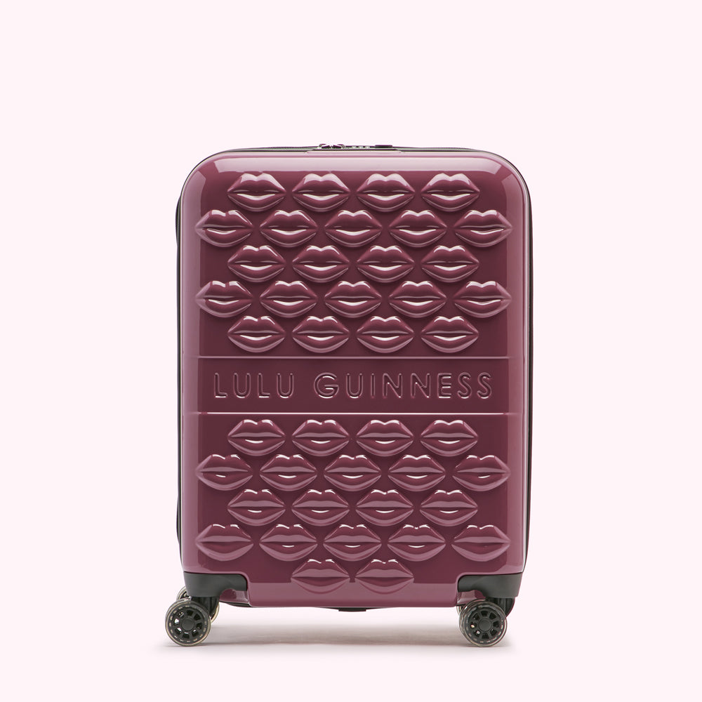 A burgundy Lulu Guinness suitcase covered in embossed lips.