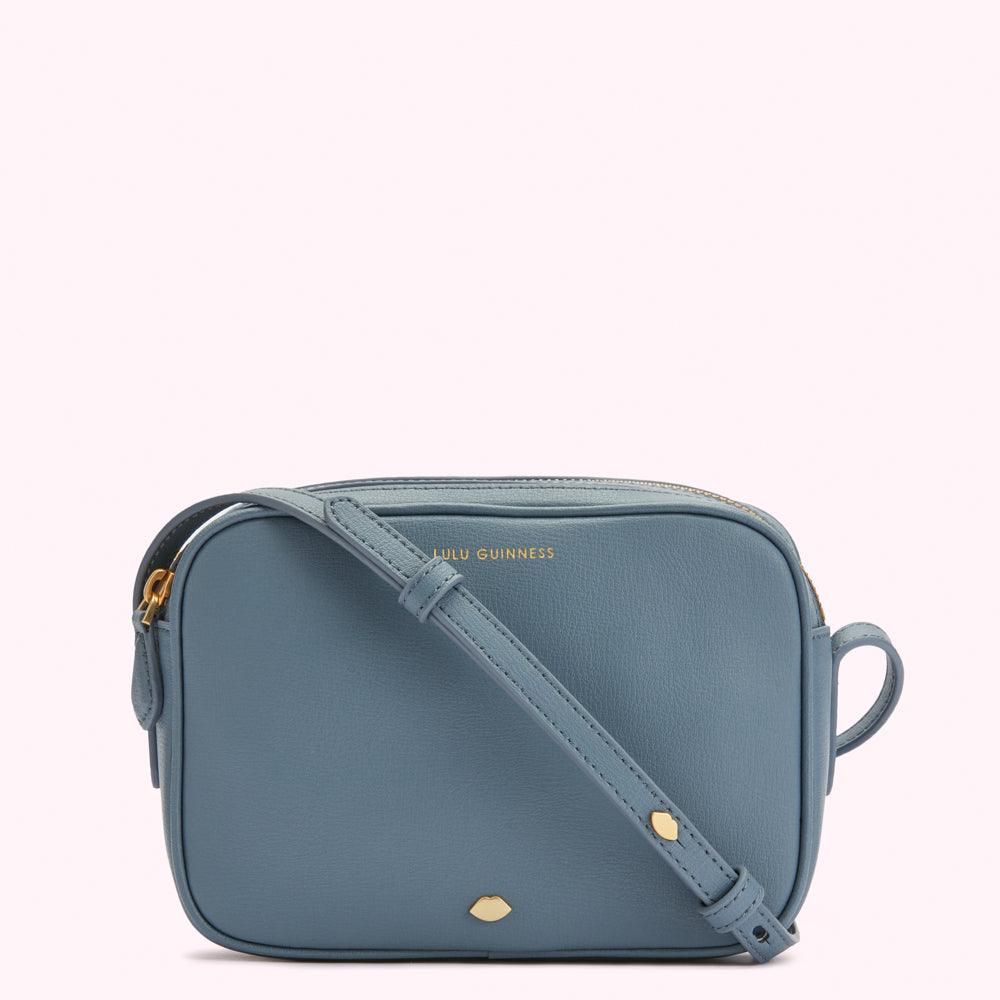 A dusty blue Lulu Guinness crossbody bag with gold hardware.