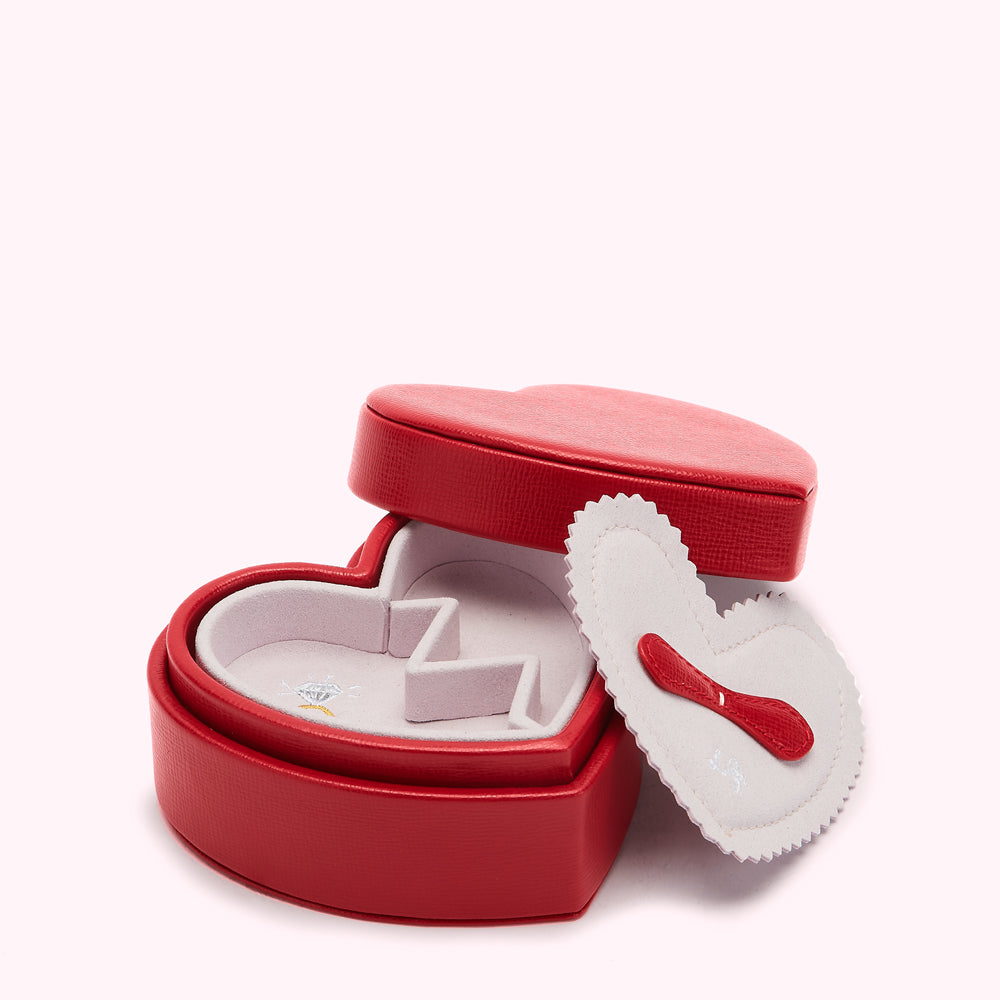 Red heart-shaped jewelry box open to reveal a light pink velvet interior with compartments.