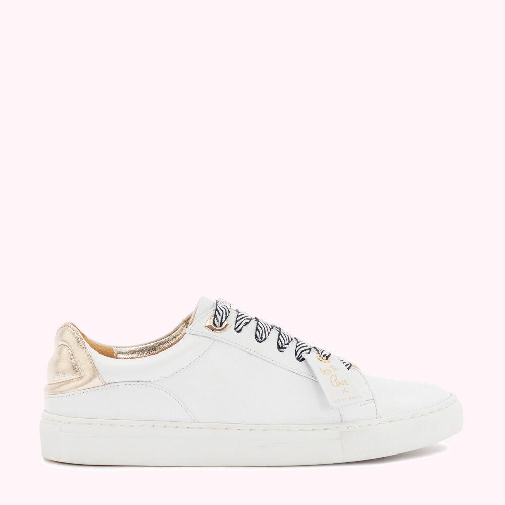 White leather sneakers with gold heel detail and zebra-print laces against a pink background.