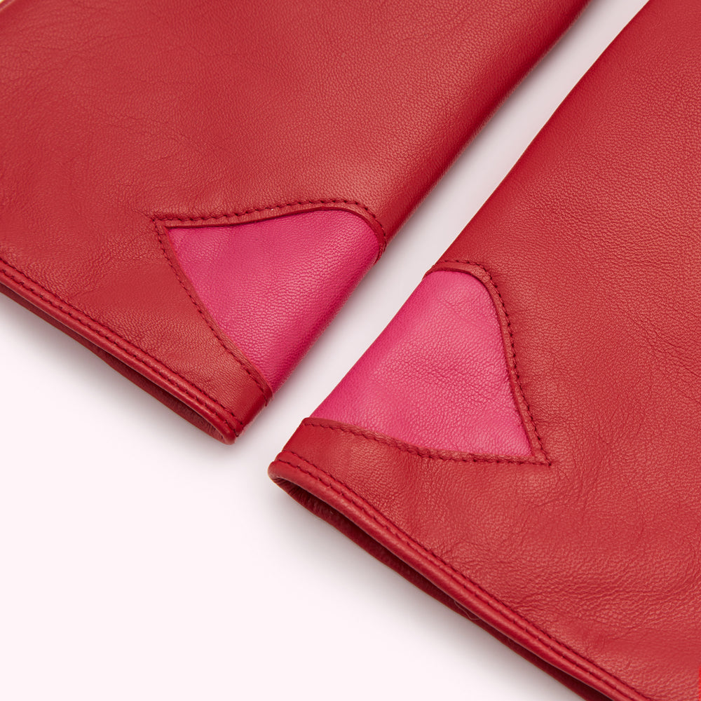 Close-up of a pair of red leather gloves with pink heart-shaped details.
