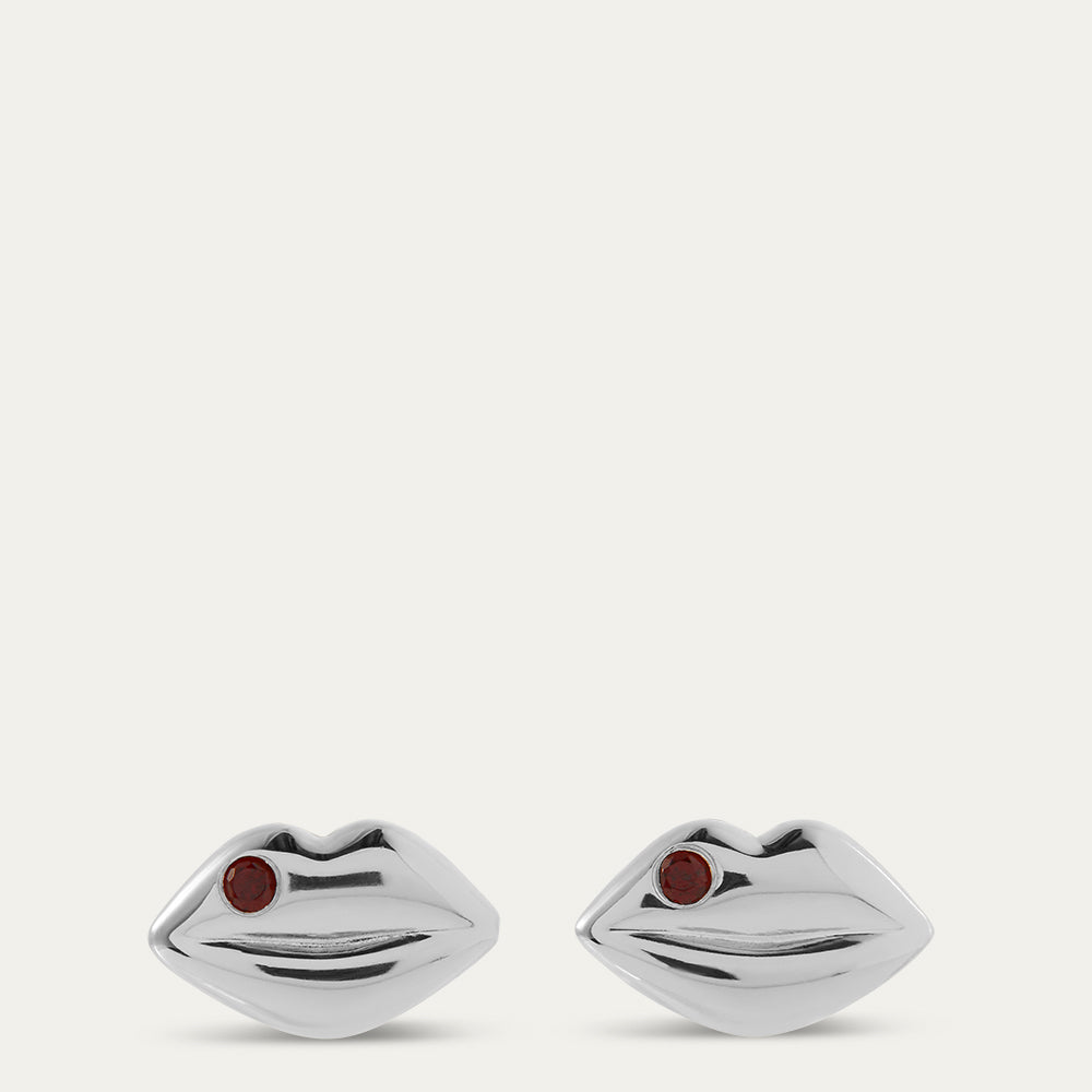 Silver lip-shaped earrings with red stones on a white background