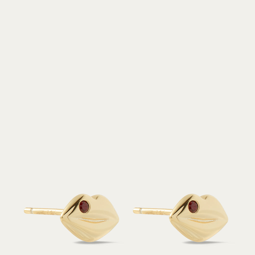 Gold earrings with red gemstones on a white background
