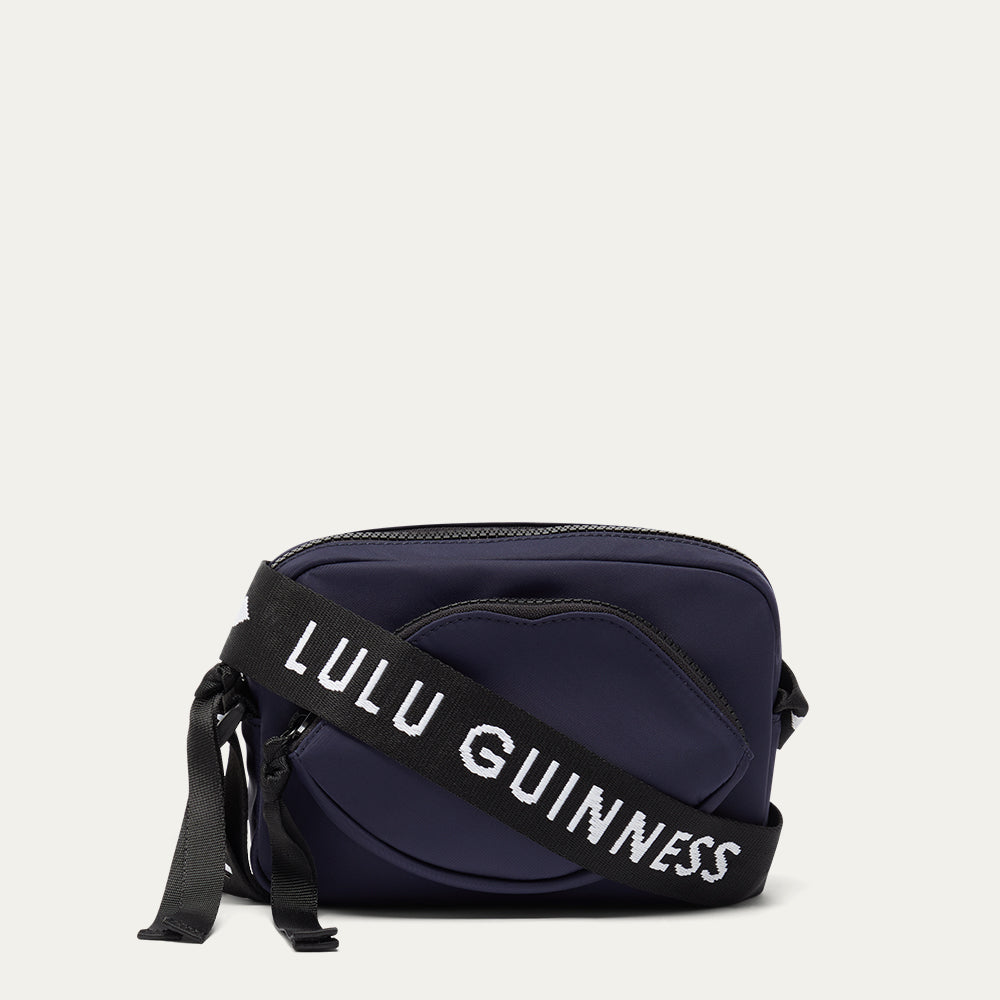 Navy blue bag with a black strap featuring 'Lulu Guinness' on a light gray background