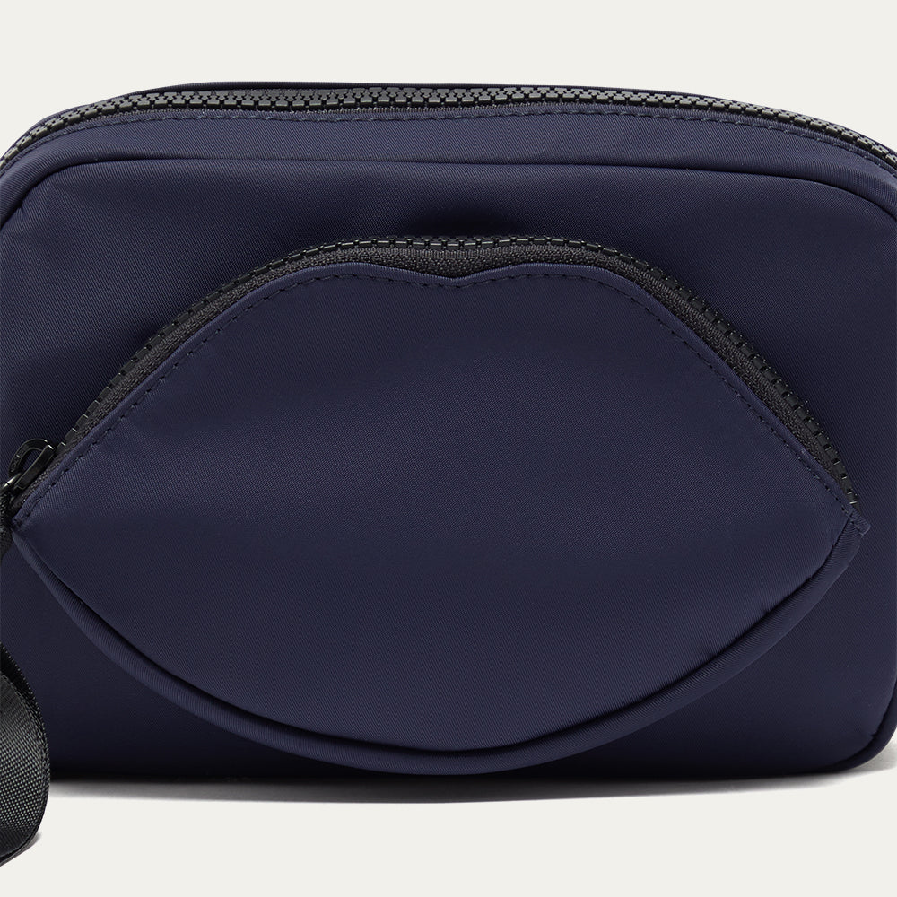 Navy blue crossbody bag with a lip shaped pocket on a white background