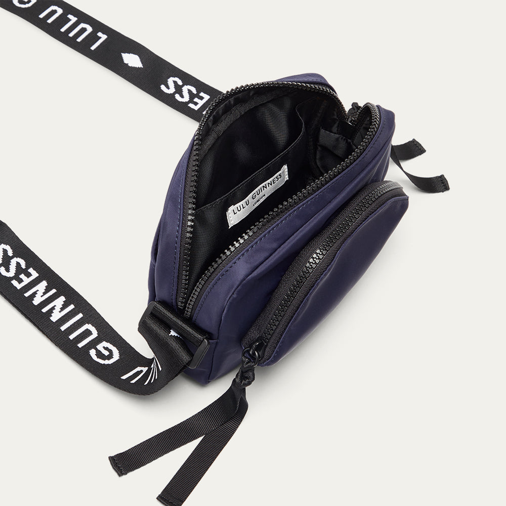 Navy blue crossbody bag with black strap featuring 'Lulu Guinness' on a white background
