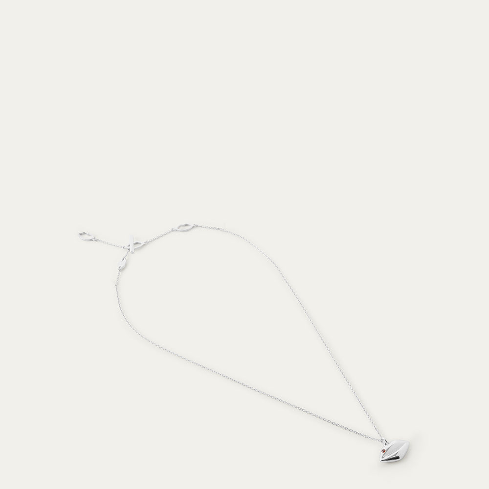 Silver necklace with a lip-shaped pendant and ruby stone on a white background