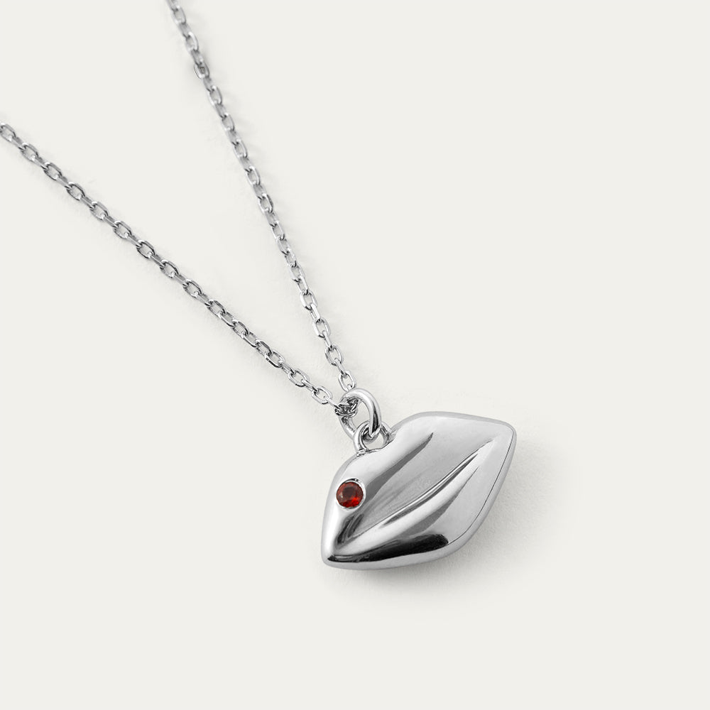 Silver necklace with a heart-shaped pendant with a ruby stone on a white background