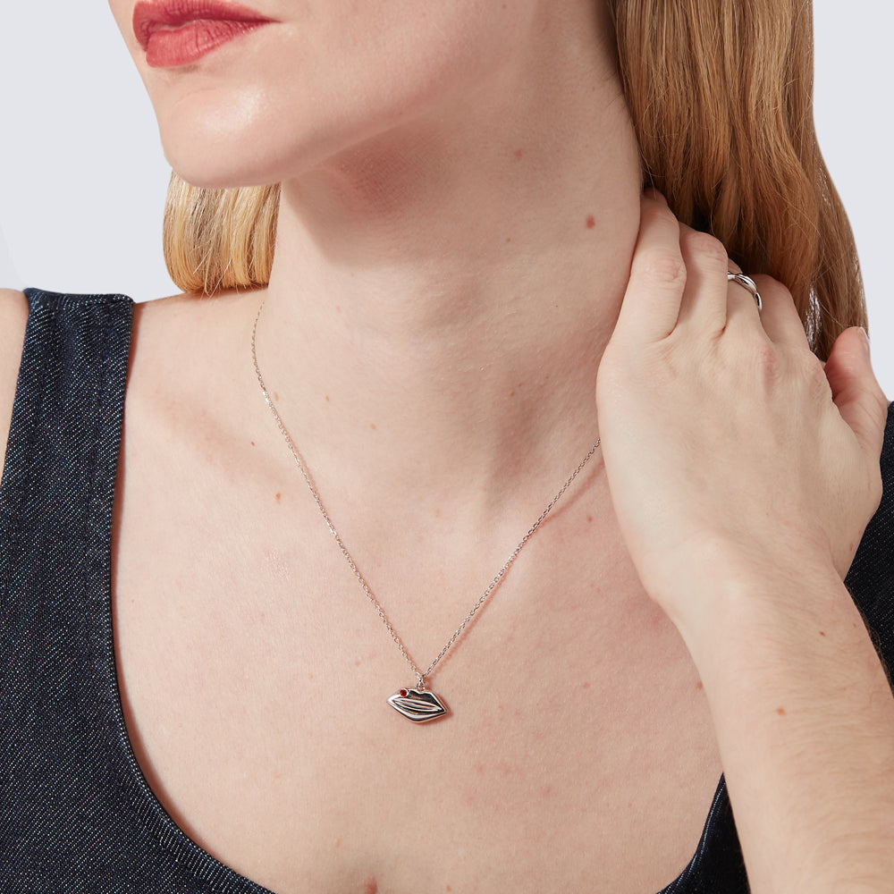 Sterling silver solid lip pendant charm on a chain featuring a inset Ruby precious stone being worn by a model.