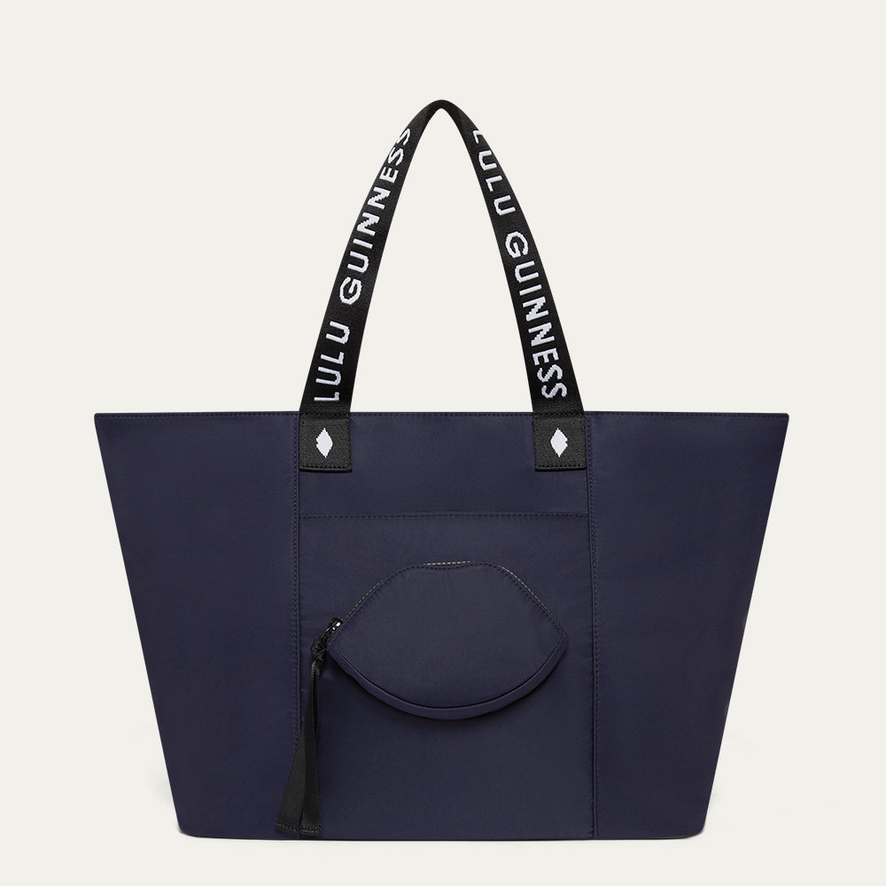 Navy tote bag with black handles featuring 'Lulu Guinness' on a light gray background