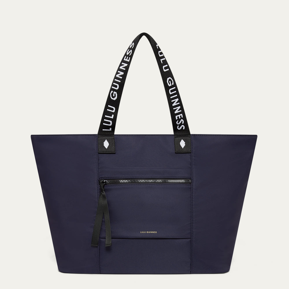 Navy tote bag with black handles featuring 'Lulu Guinness' on a light gray background