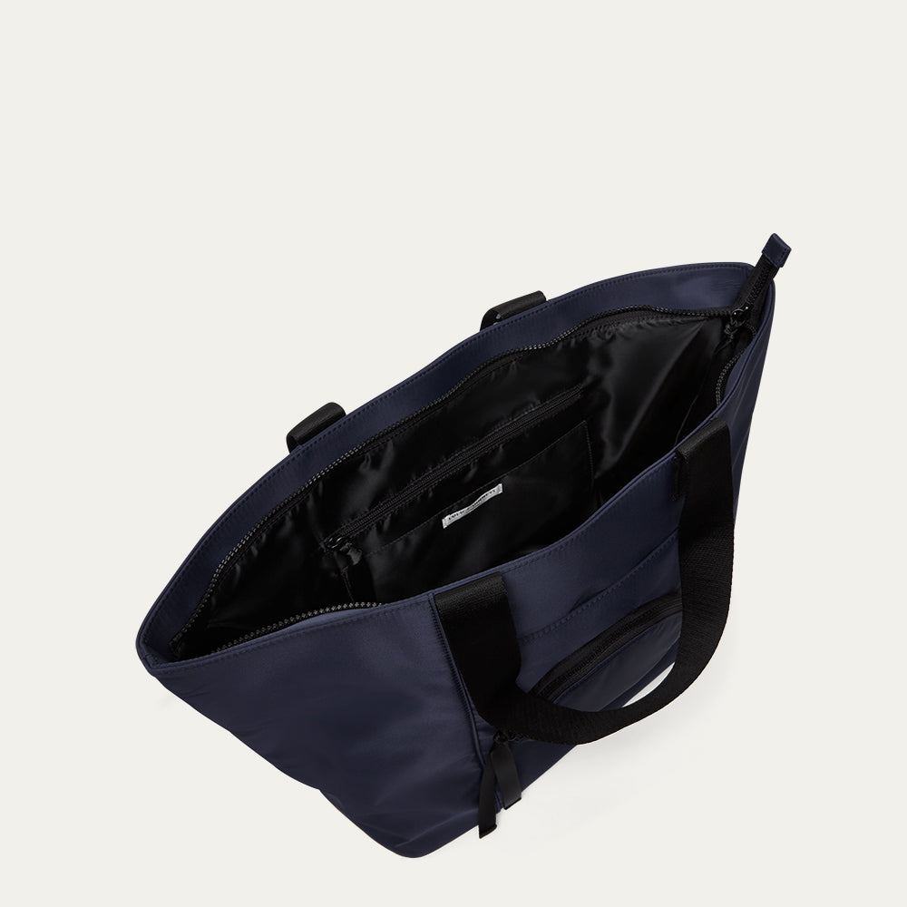 Navy blue bag with open revealing the lining on a light gray background