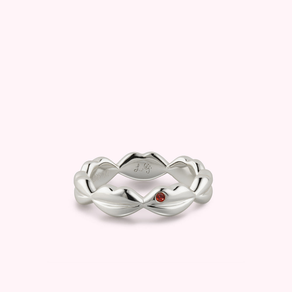 Sterling silver lip ring with inset Ruby stone laying flat.