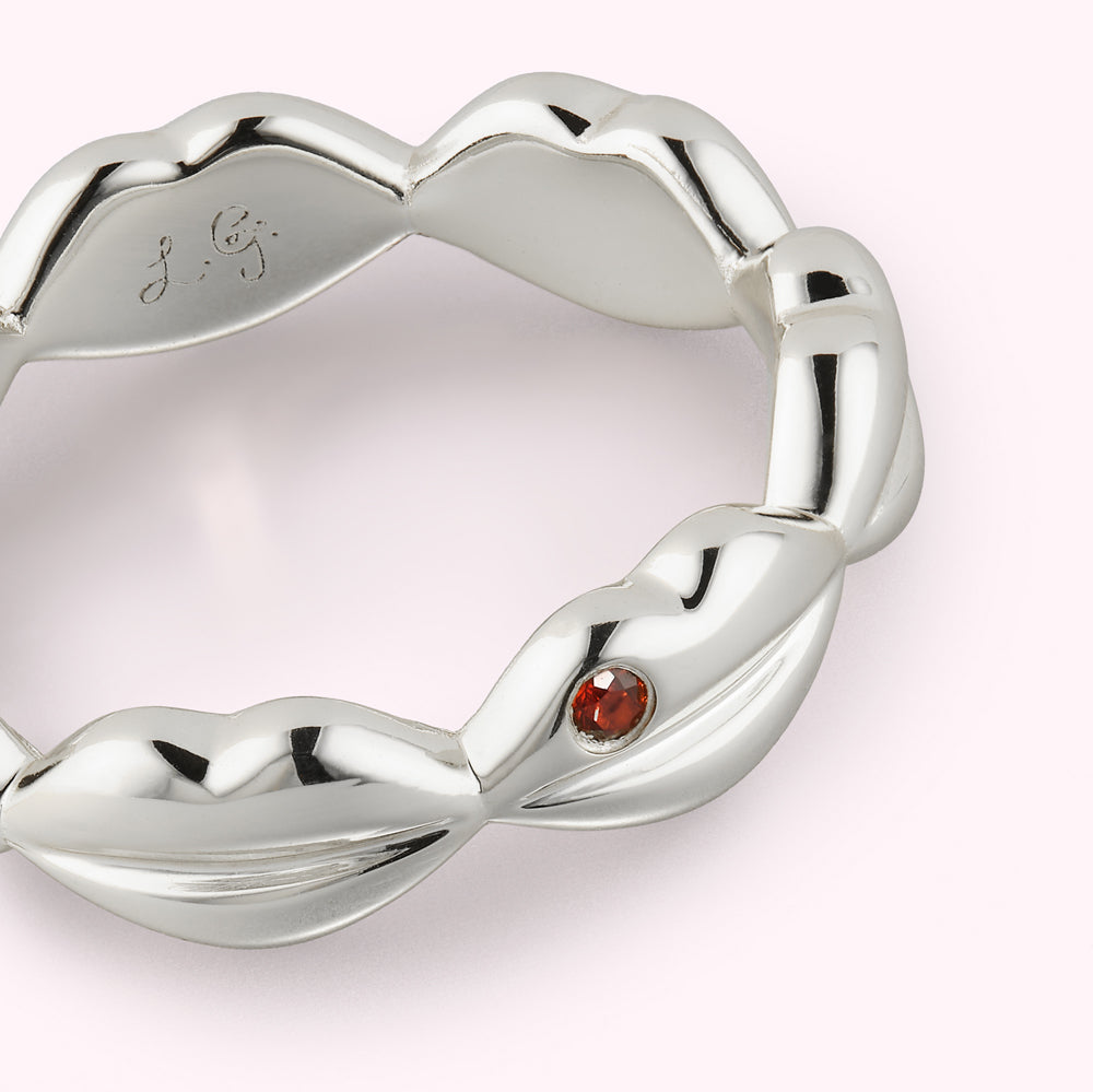 Close up detail on sterling silver lip detail ring with inset ruby stone and engraved brand logo inside the band.