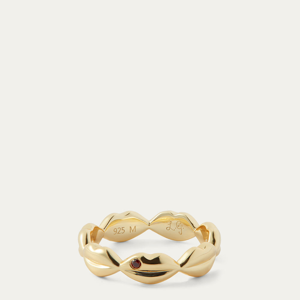 Gold ring with a red gemstone on a white background