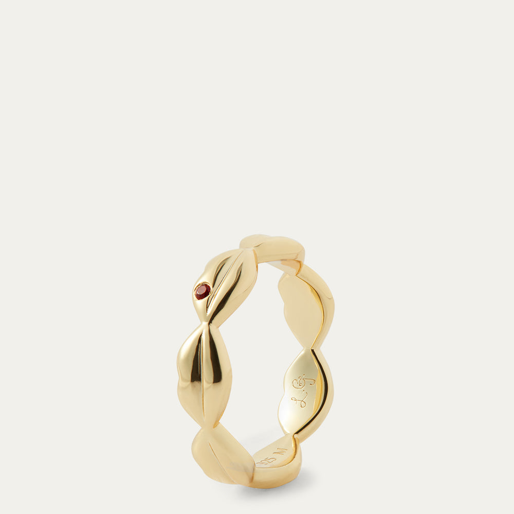 Gold ring with a small red gemstone on a light gray background