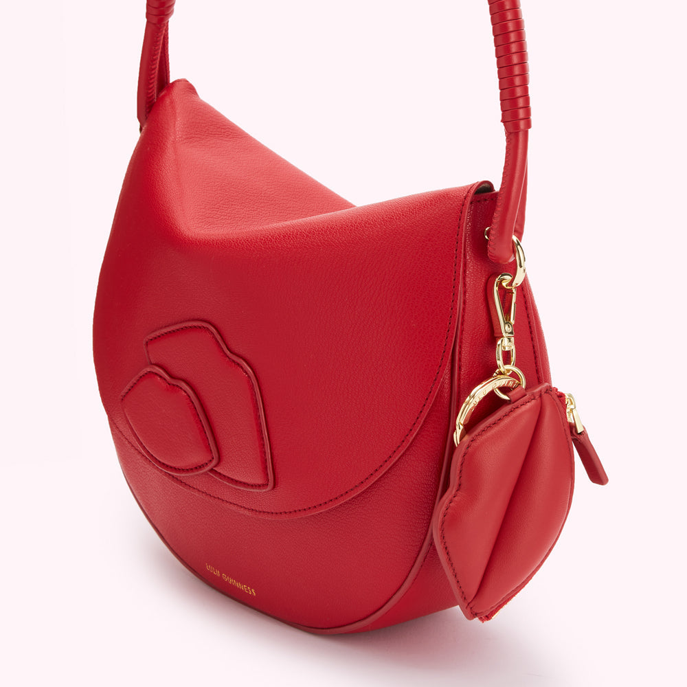 Red leather Lulu Guinness handbag with a gold-tone clasp and a lip-shaped keychain.