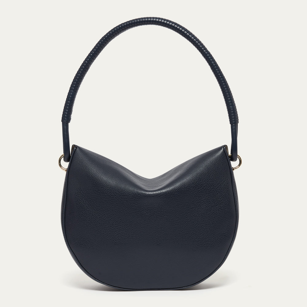 Back image of a navy blue leather shoulder bag with a corded handle on a light gray background