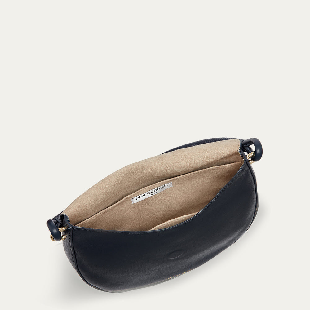 Inside image of a navy leather handbag with beige interior on a light gray background